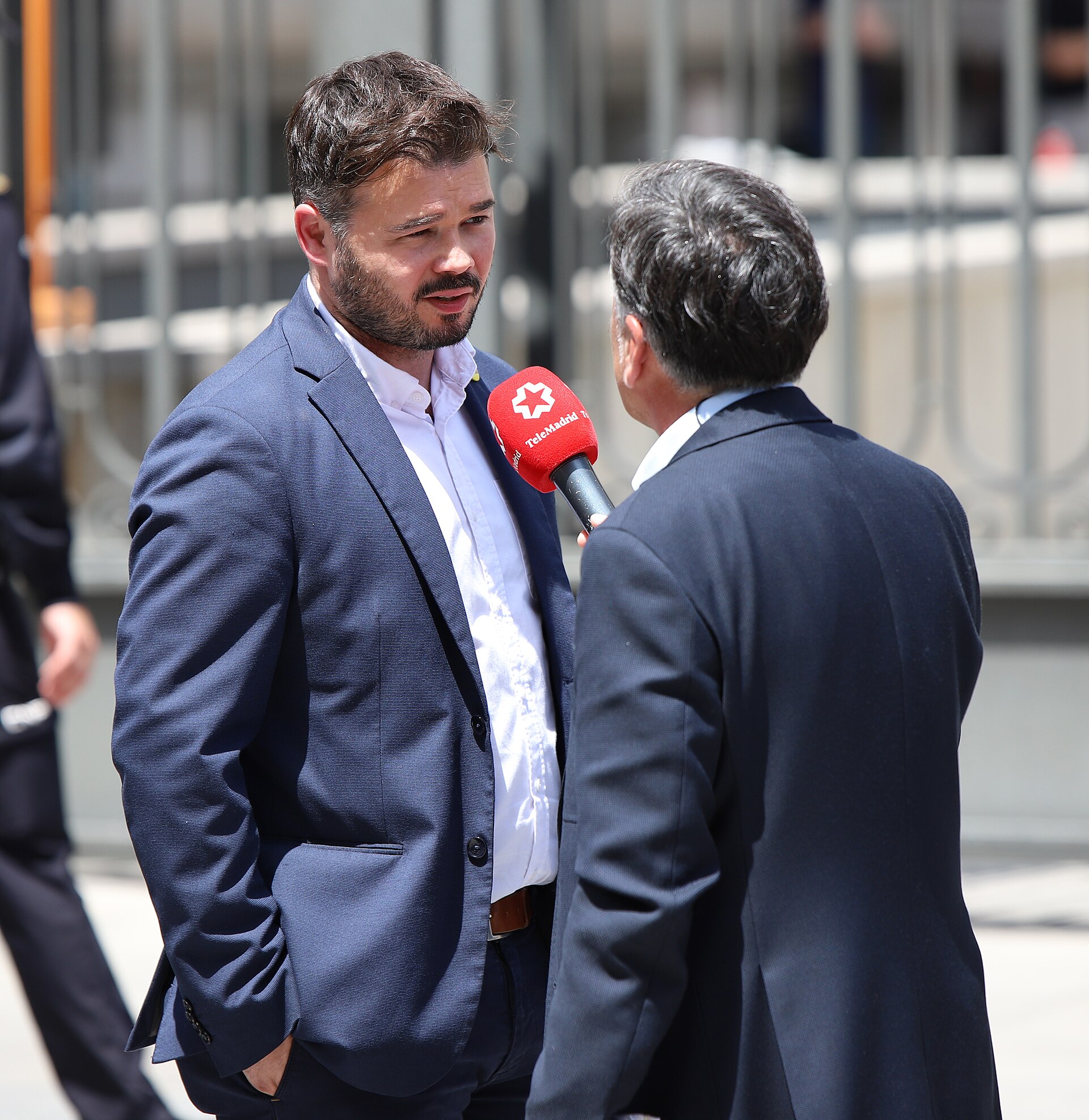 Un hombre con traje habla con un periodista que sostiene un micrófono.