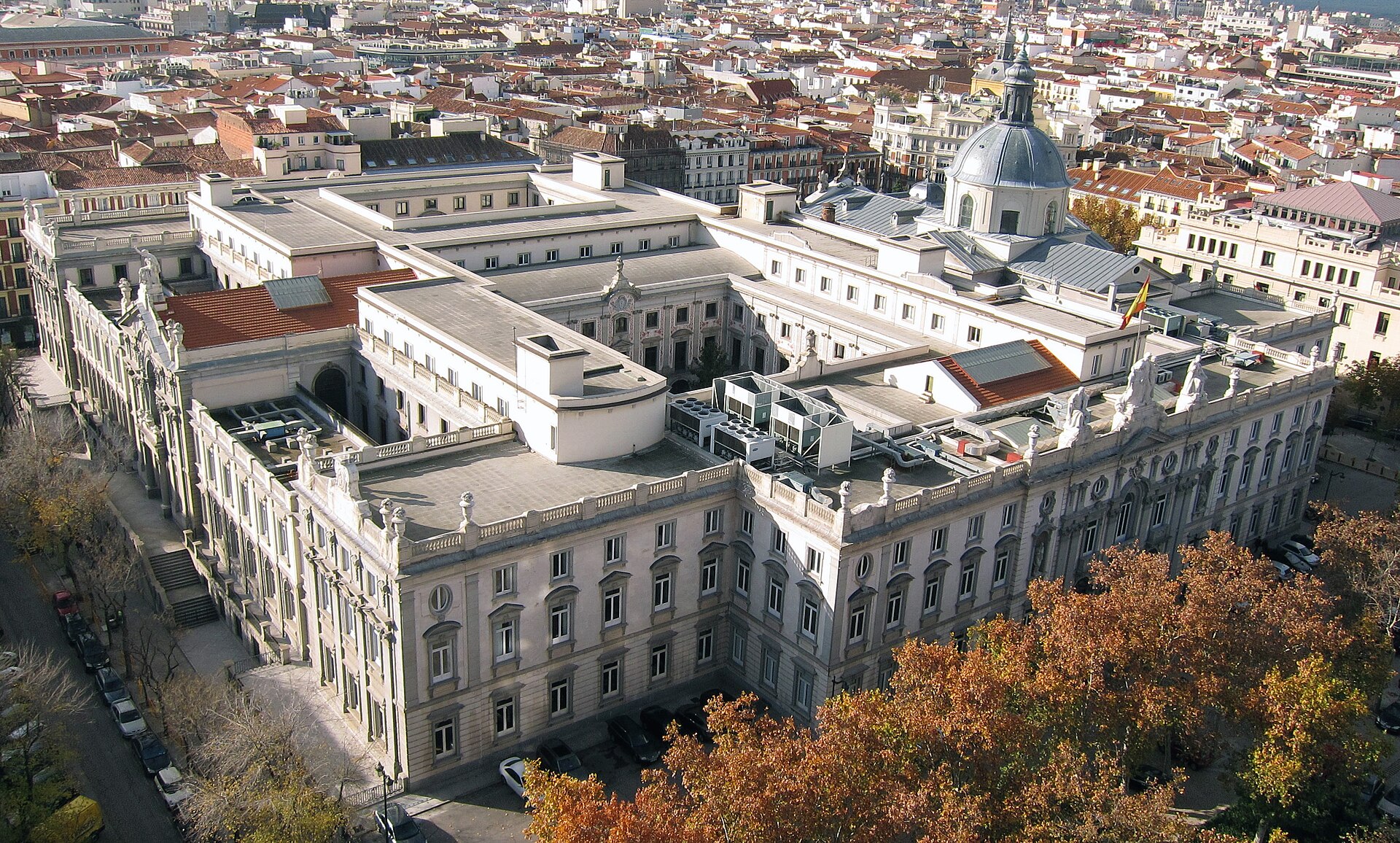 Vista aérea de un edificio con patios interiores y una cúpula, rodeado de viviendas.