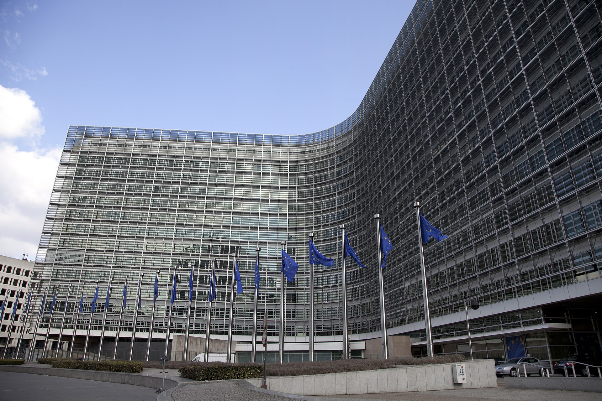 Edificio acristalado ante varias banderas de la Unión Europea.