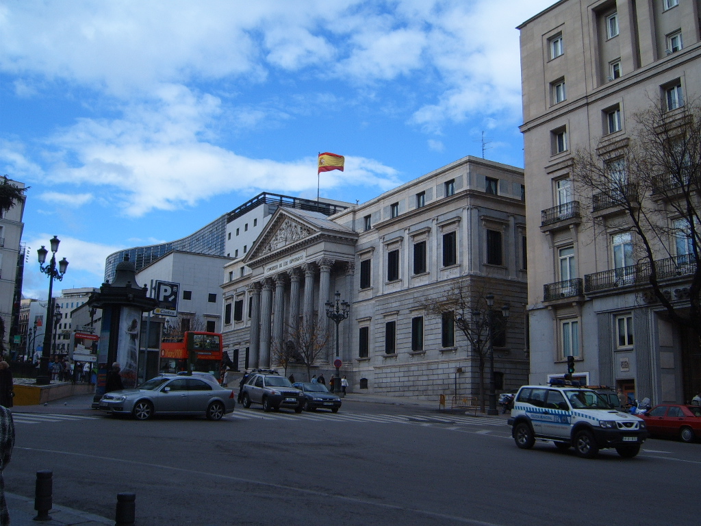 Vista exterior del Congreso de los Diputados desde una calle, con tráfico frente al edificio.