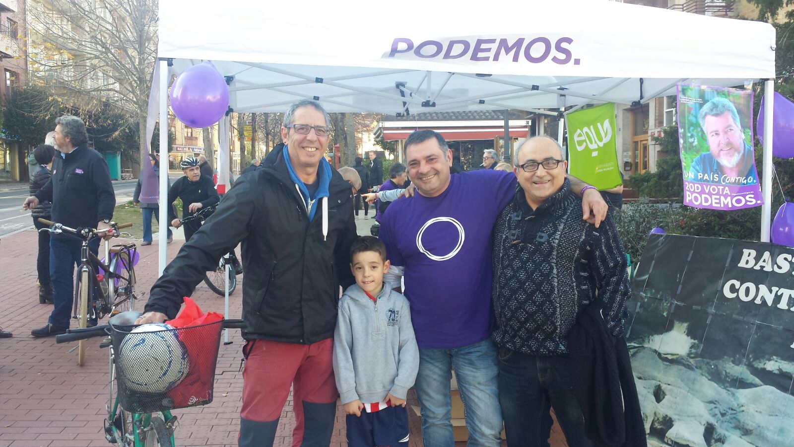 Una carpa con el rótulo de Podemos y una bandera de Equo, junto a varias personas posando.