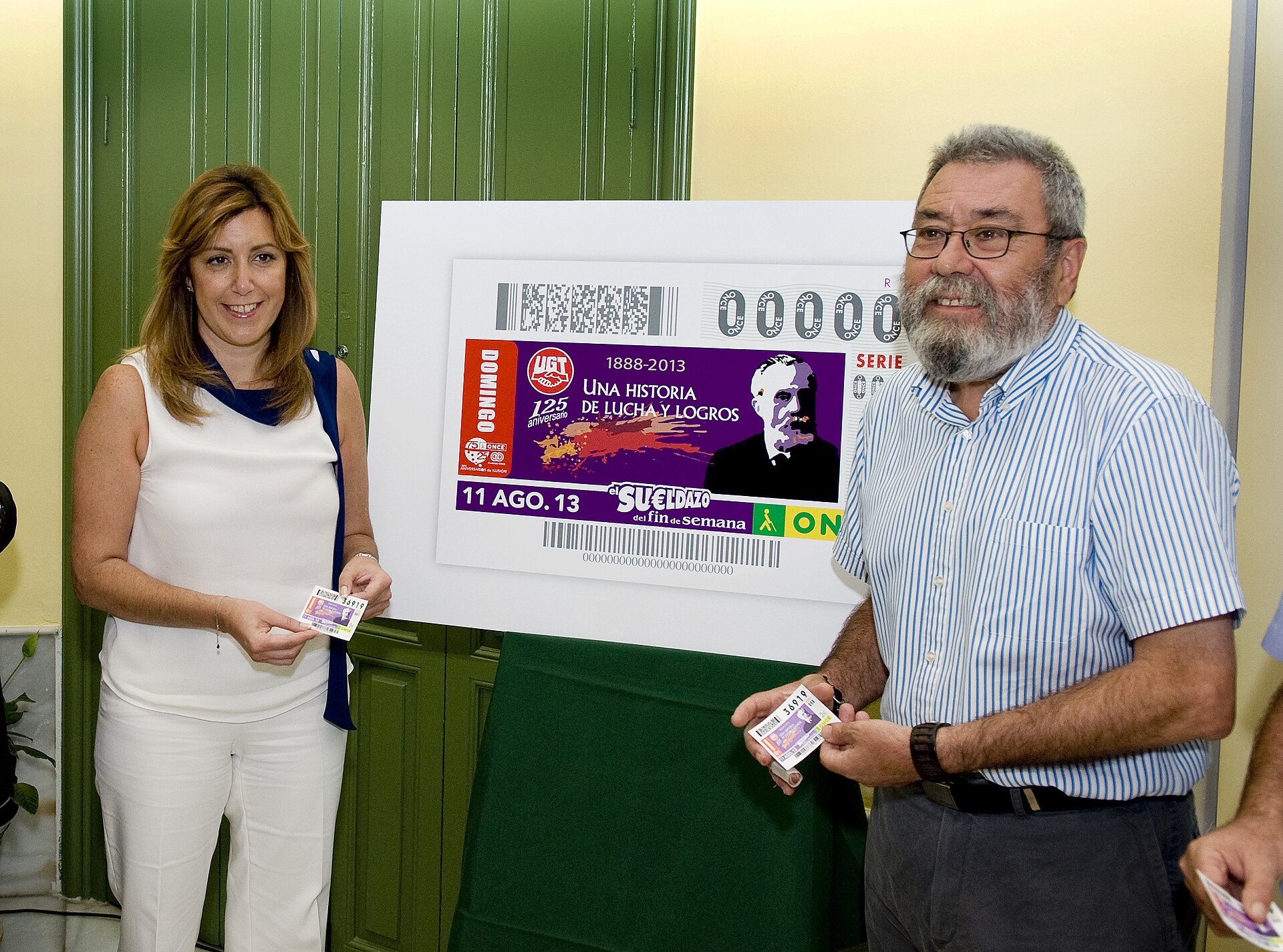 Dos personas posan junto a un cartel de un cupón con el logotipo de UGT.