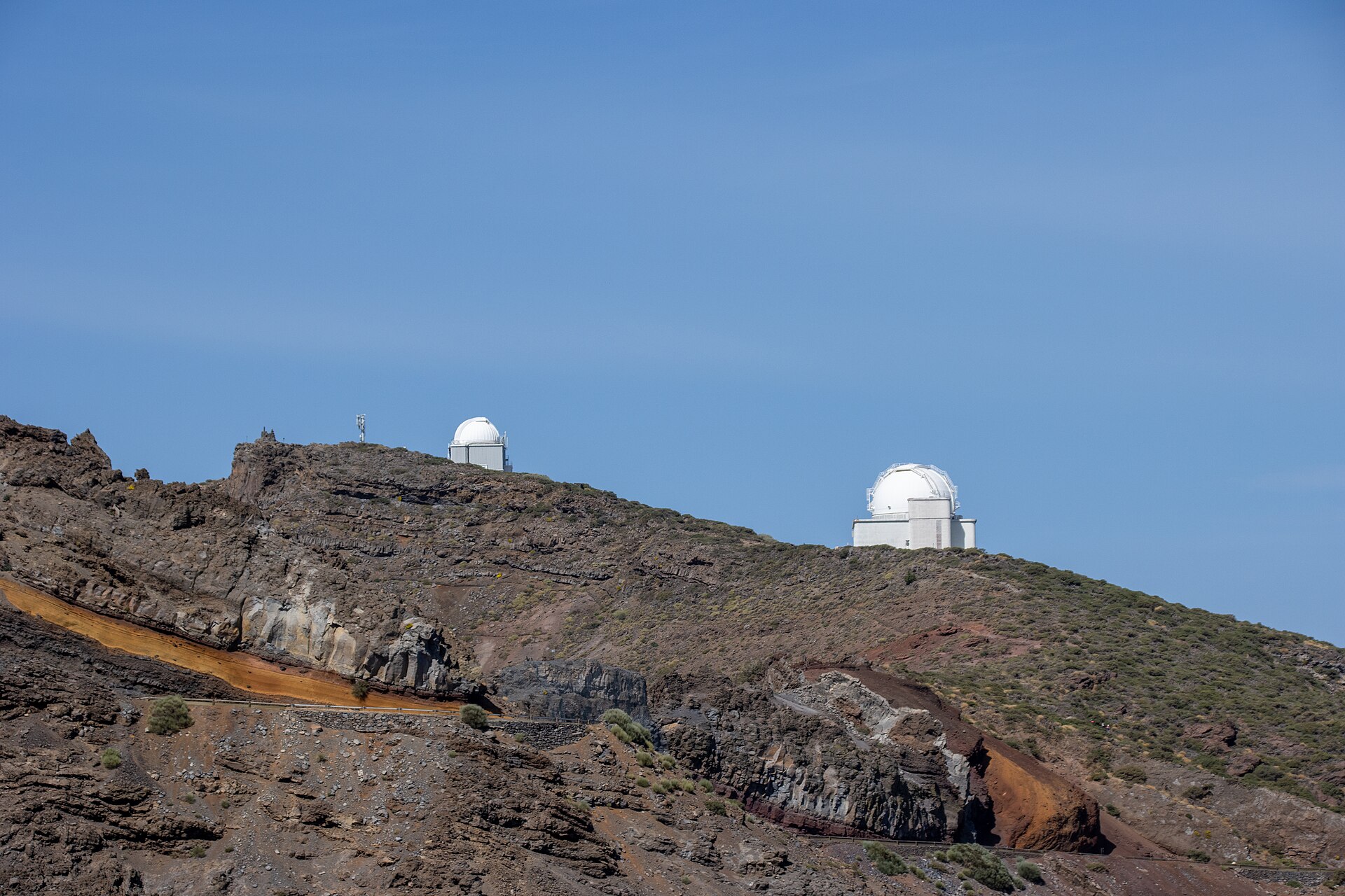Dos edificios con cúpulas blancas se sitúan sobre una ladera rocosa.