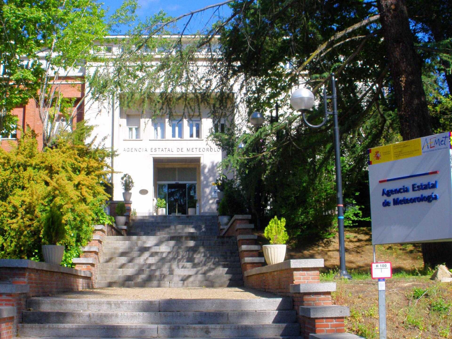 Entrada ajardinada de un edificio institucional.