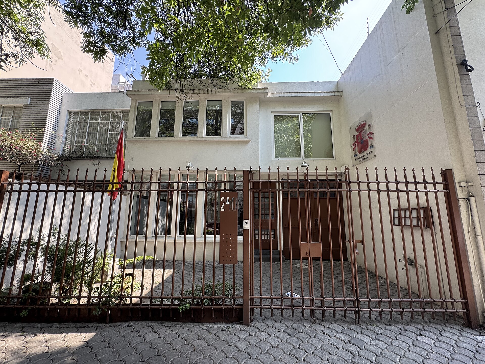 Fachada de un edificio oficial con una bandera española y un escudo en la entrada.