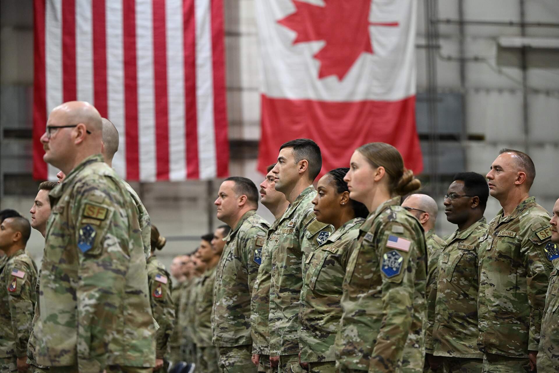 Personal militar formado ante las banderas de Estados Unidos y Canadá.