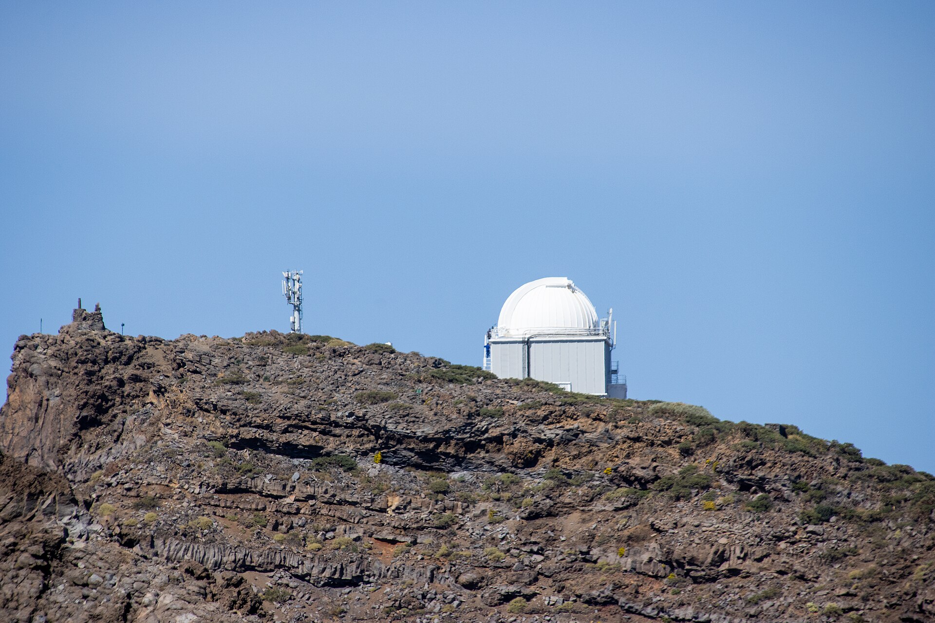 Una cúpula blanca y una antena de comunicaciones sobresalen sobre una cresta rocosa.