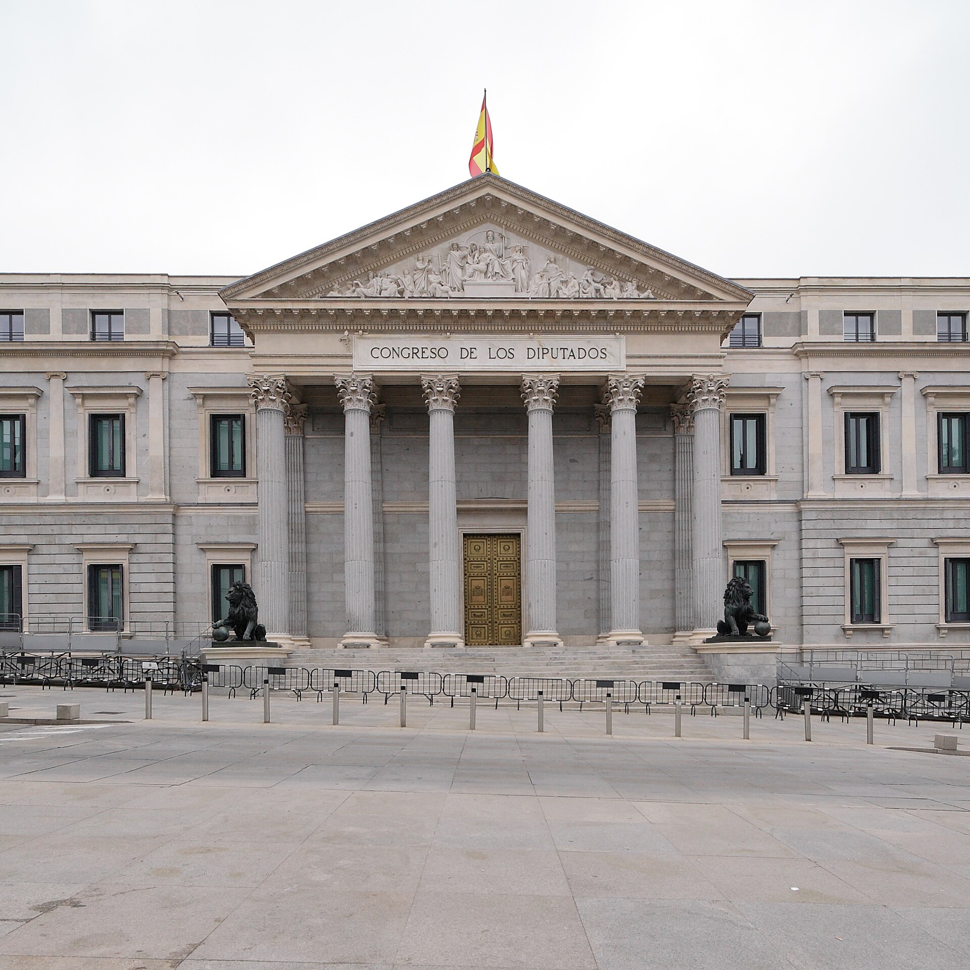 Vista frontal de un edificio con columnas, escalinata y dos esculturas de leones.