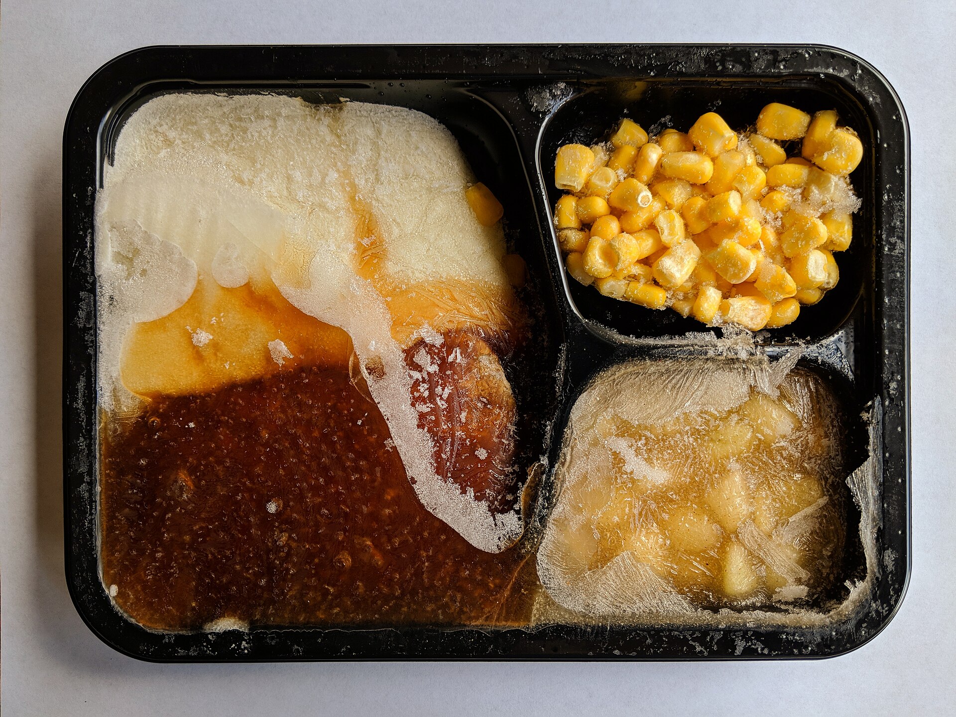 Bandeja compartimentada con varios alimentos congelados.