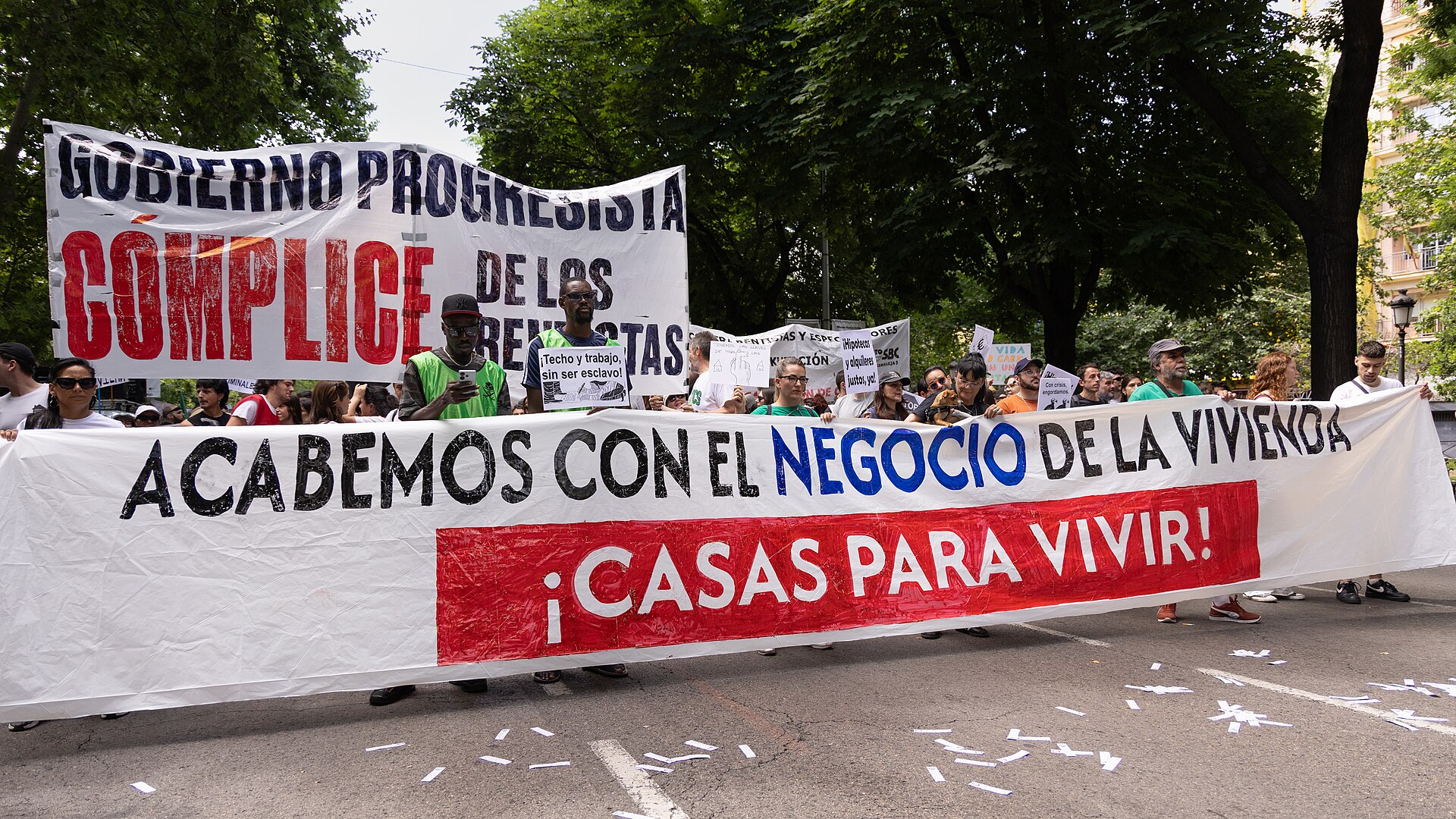 Manifestantes sostienen una pancarta que reclama casas para vivir y pide acabar con el negocio de la vivienda.