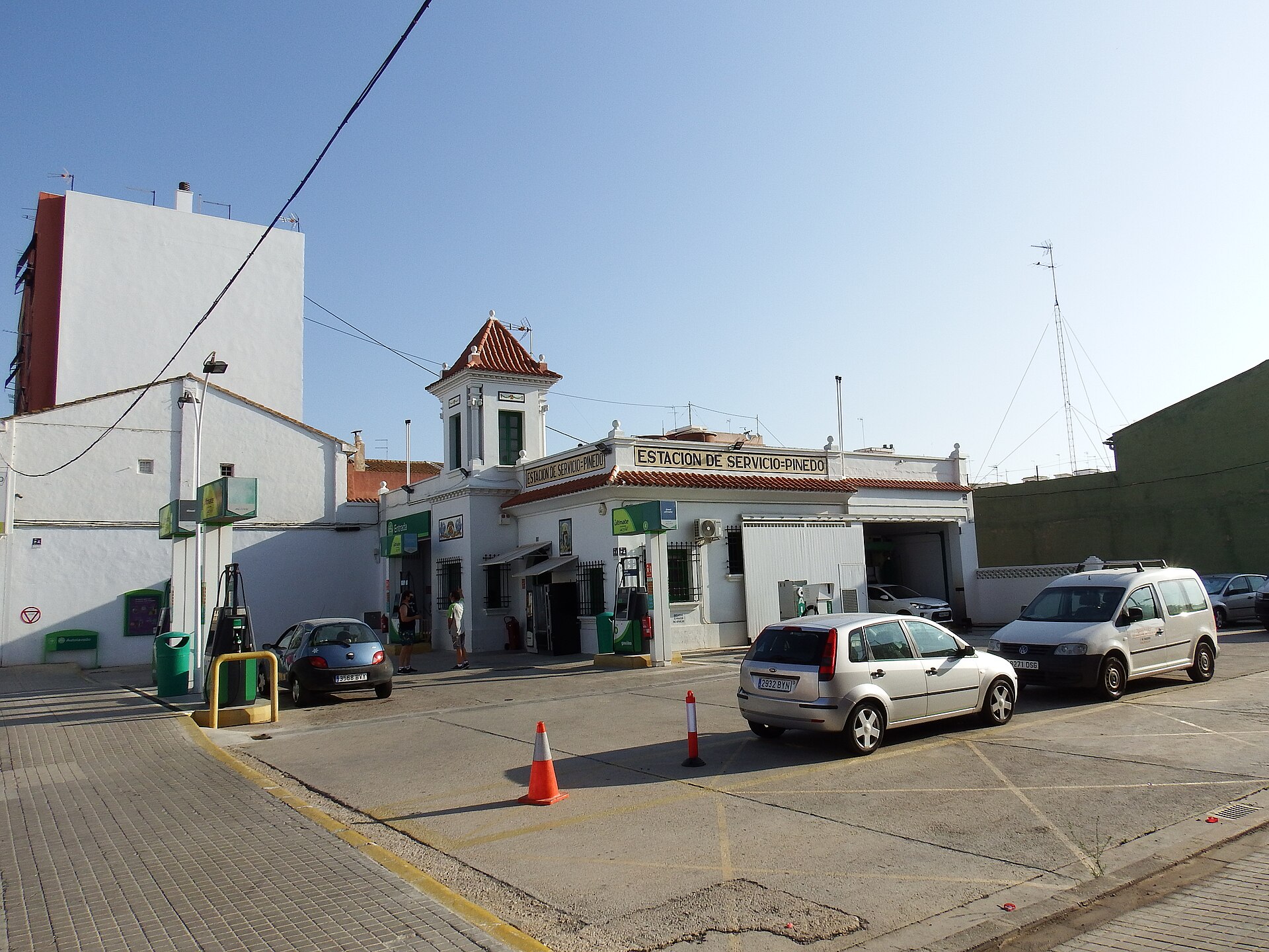 Una estación de servicio con surtidores y varios vehículos en el exterior.