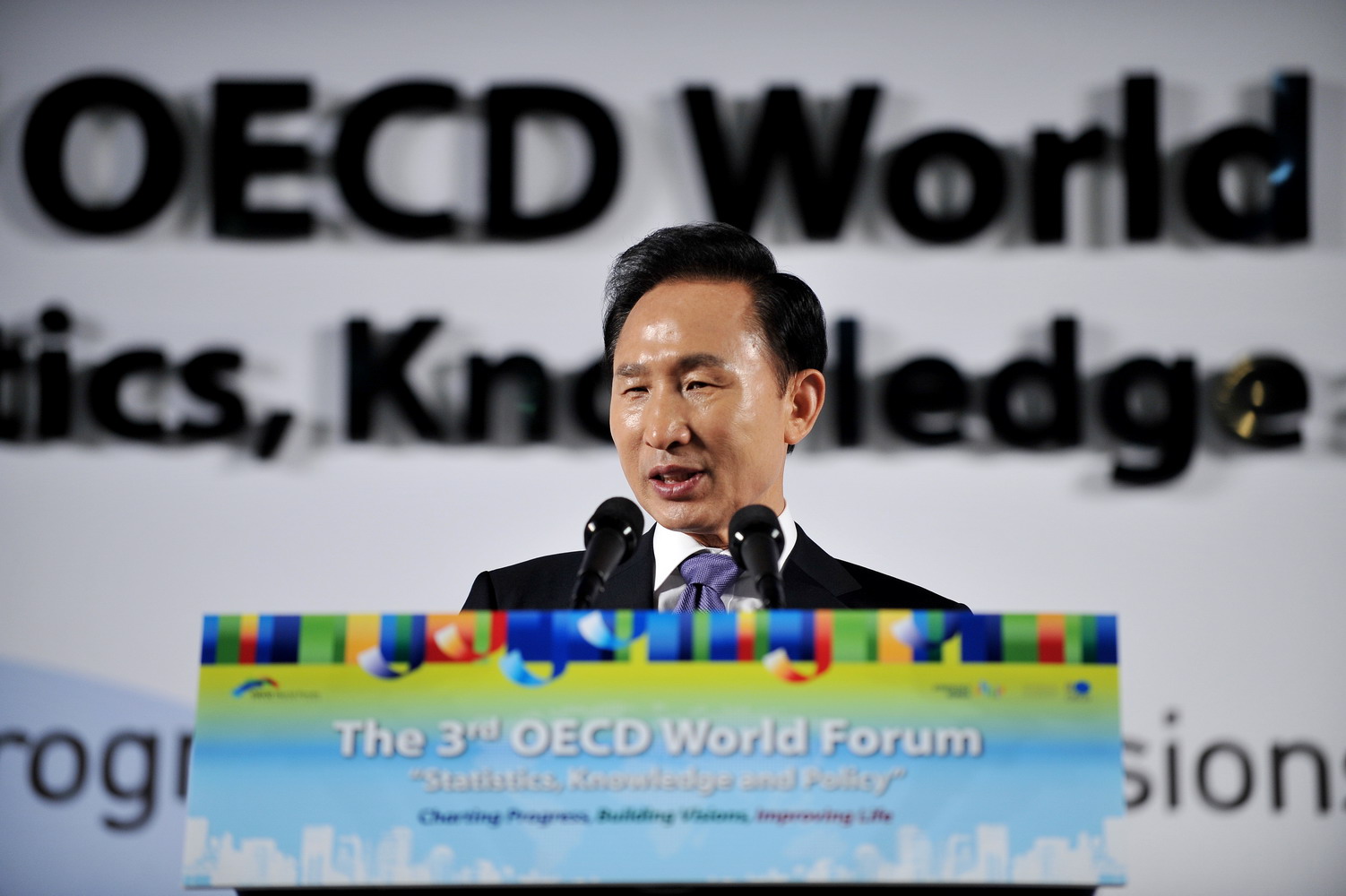 Un hombre habla ante un atril con el rótulo «OECD World Forum» al fondo.