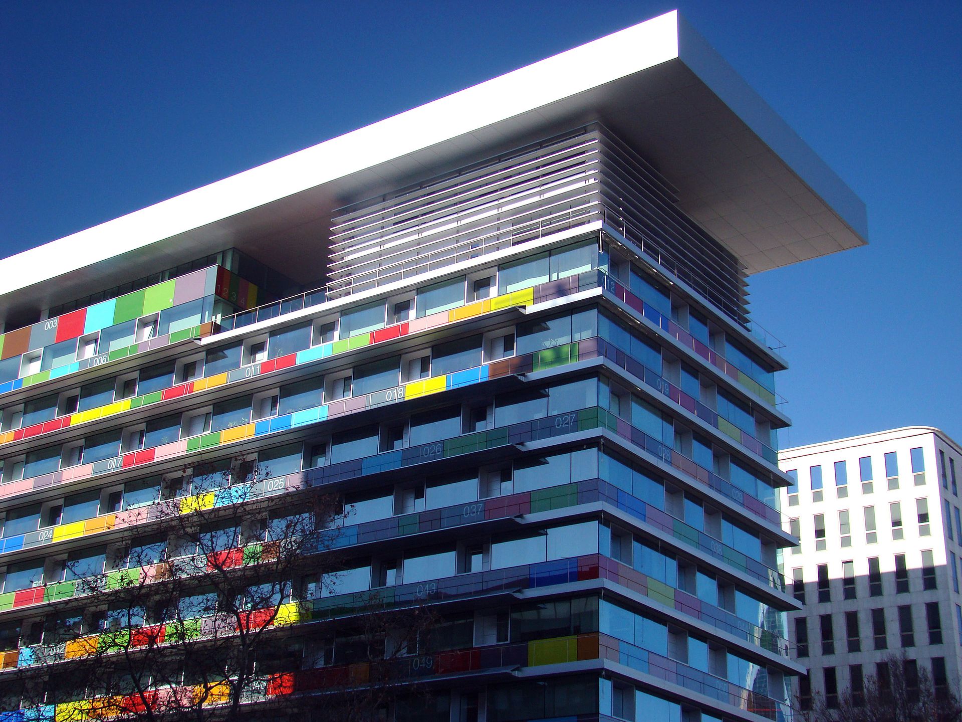 Vista de un edificio de varias plantas con franjas de colores en la fachada.