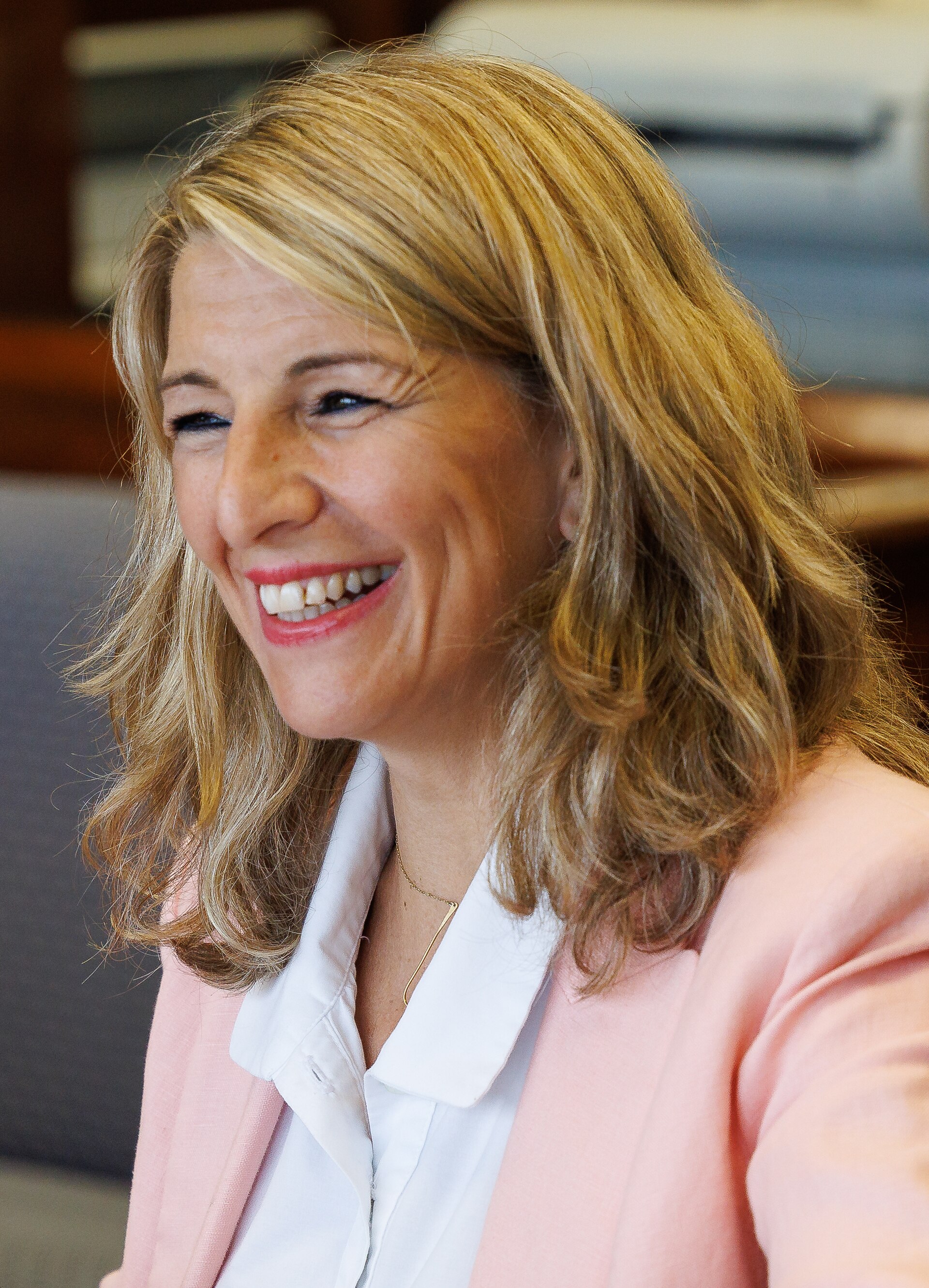 Primer plano de una mujer sonriente con una chaqueta de color rosa.