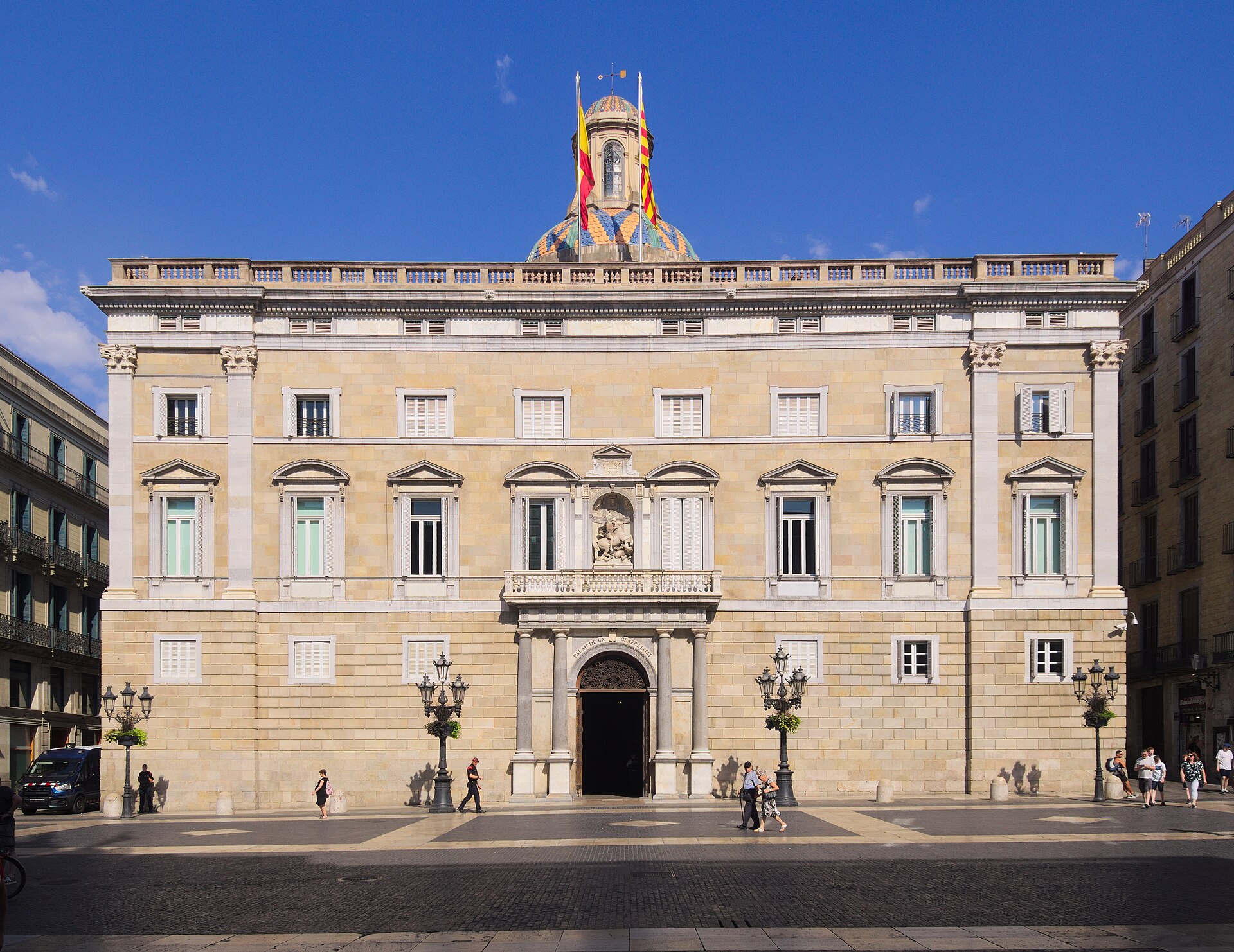 Fachada de un edificio institucional con dos banderas en la torre central.