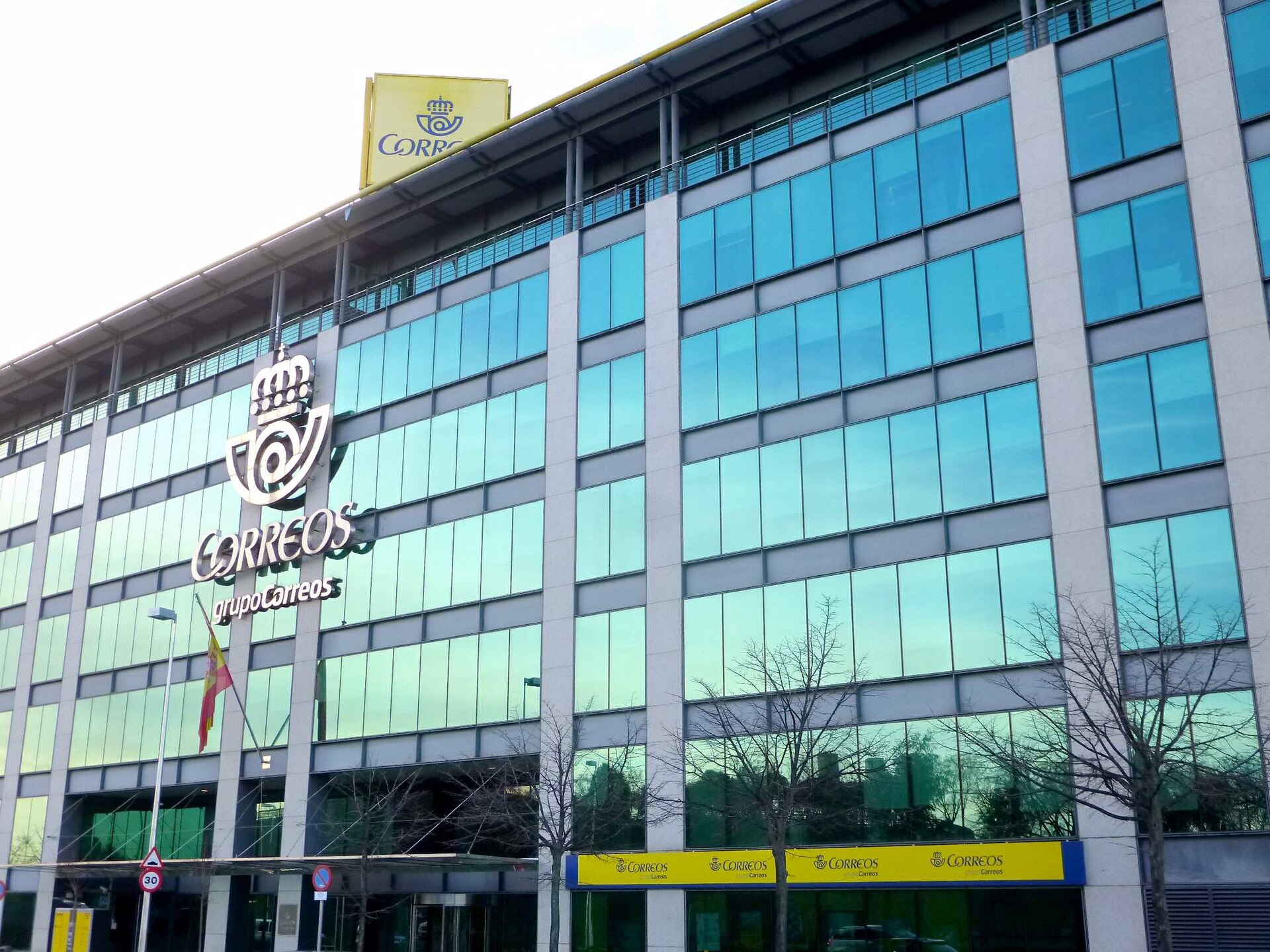 Fachada acristalada de un edificio con el rótulo de Correos.