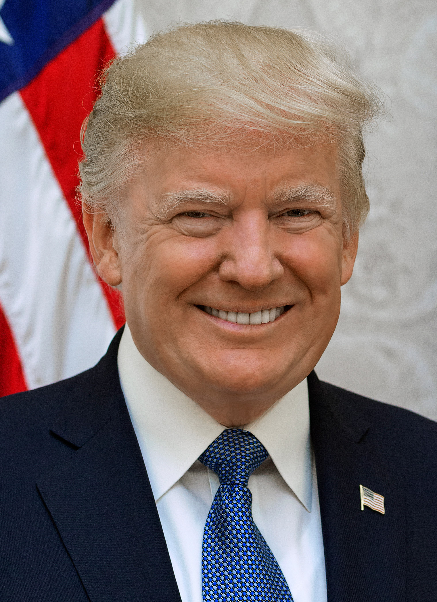 Primer plano de un hombre sonriente con traje y corbata, ante una bandera de Estados Unidos.
