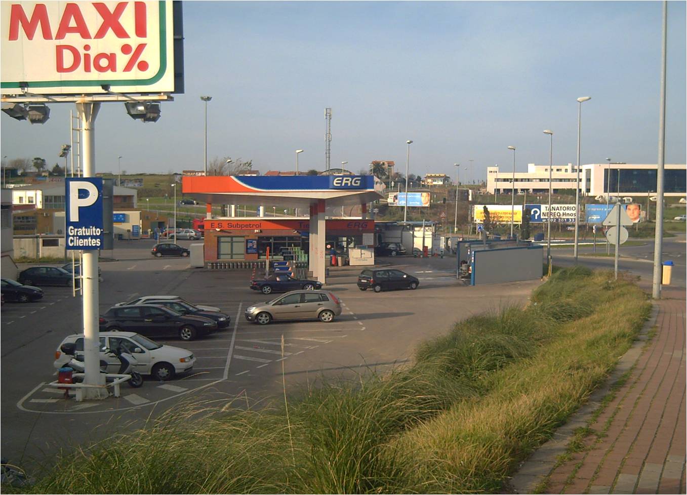 Una estación de servicio vista desde una zona de aparcamiento, junto a una vía urbana.