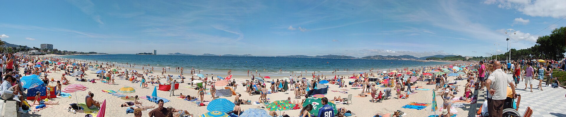 Numerosas personas ocupan una playa soleada junto al mar.