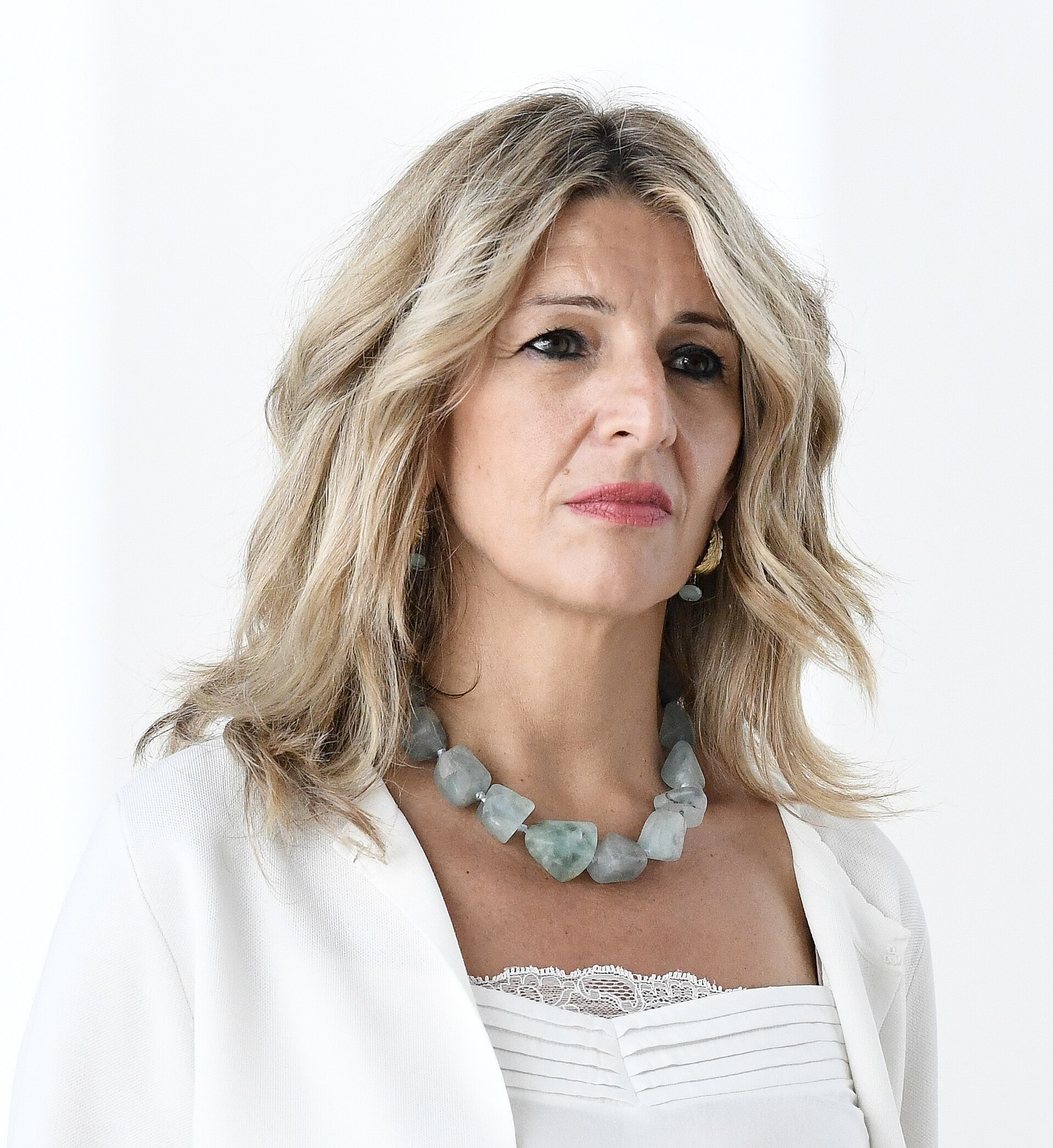 Primer plano de una mujer con el cabello rubio y una chaqueta blanca.