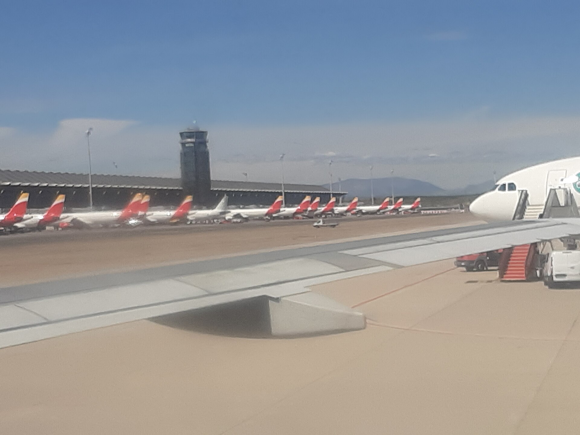 Varios aviones estacionados en la plataforma, vistos desde la ventanilla de otra aeronave.