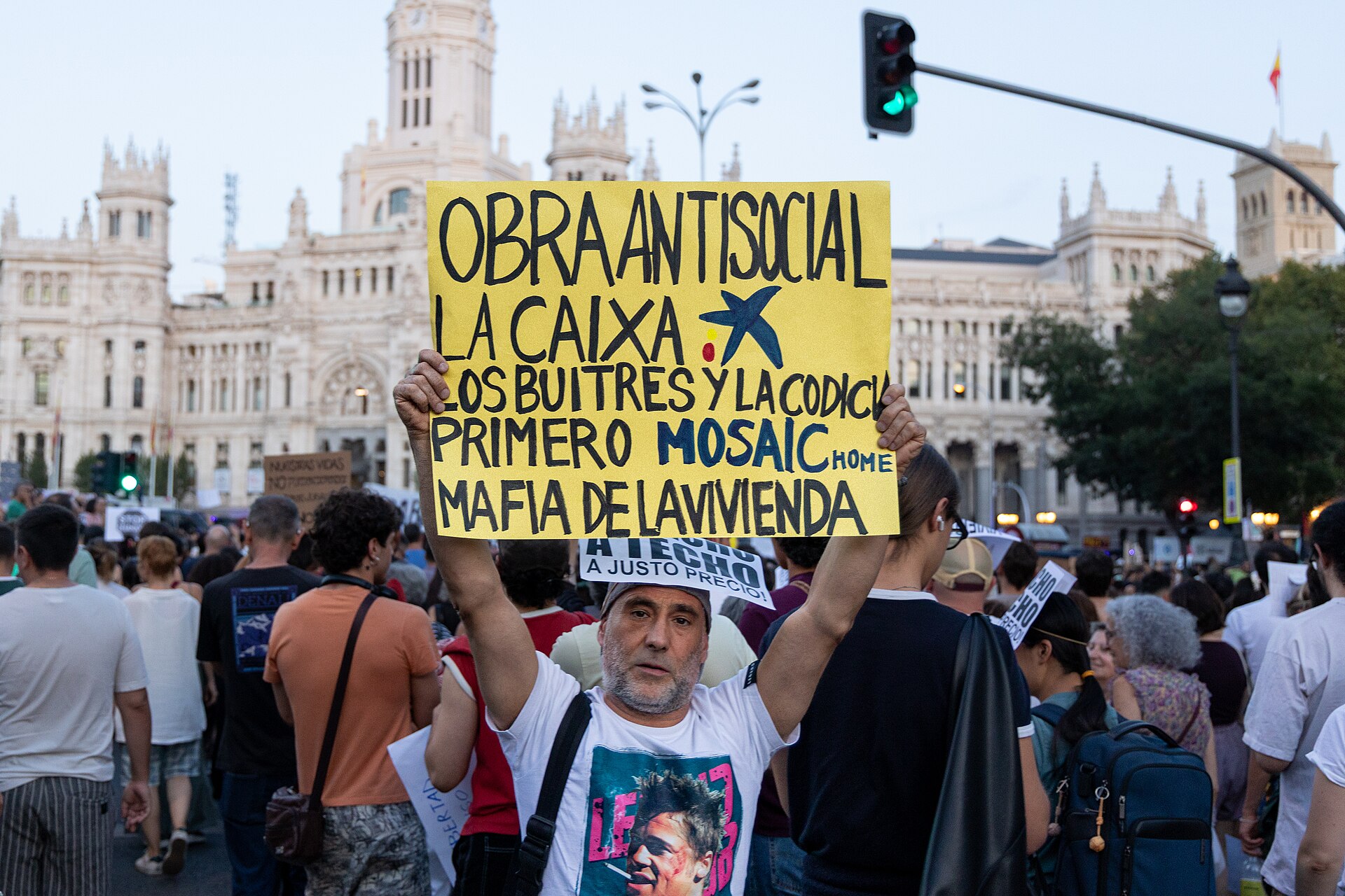 Una pancarta sobre vivienda se alza entre la multitud durante una concentración.
