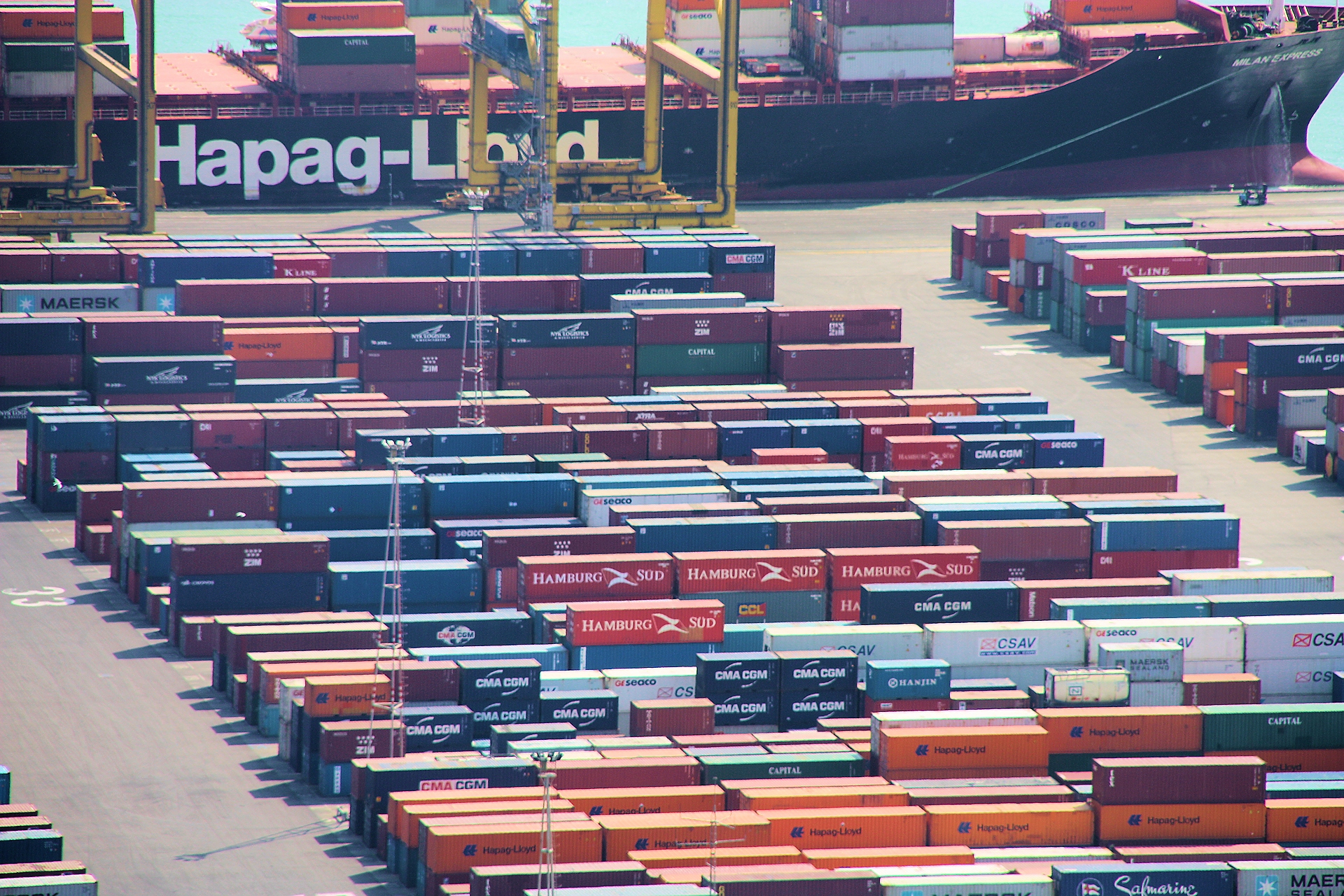 Contenedores apilados junto a un buque en una terminal portuaria.