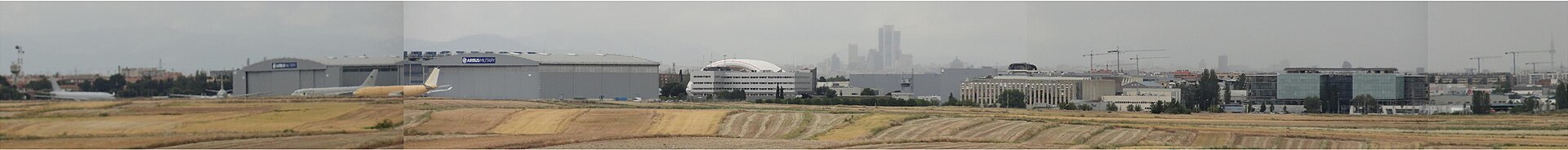 Instalaciones industriales con varios hangares y rótulos de Airbus; al fondo, una aeronave.