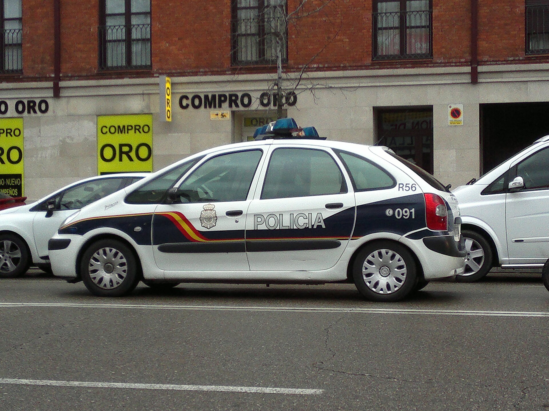 Un coche patrulla con distintivos policiales, estacionado junto a otros vehículos.