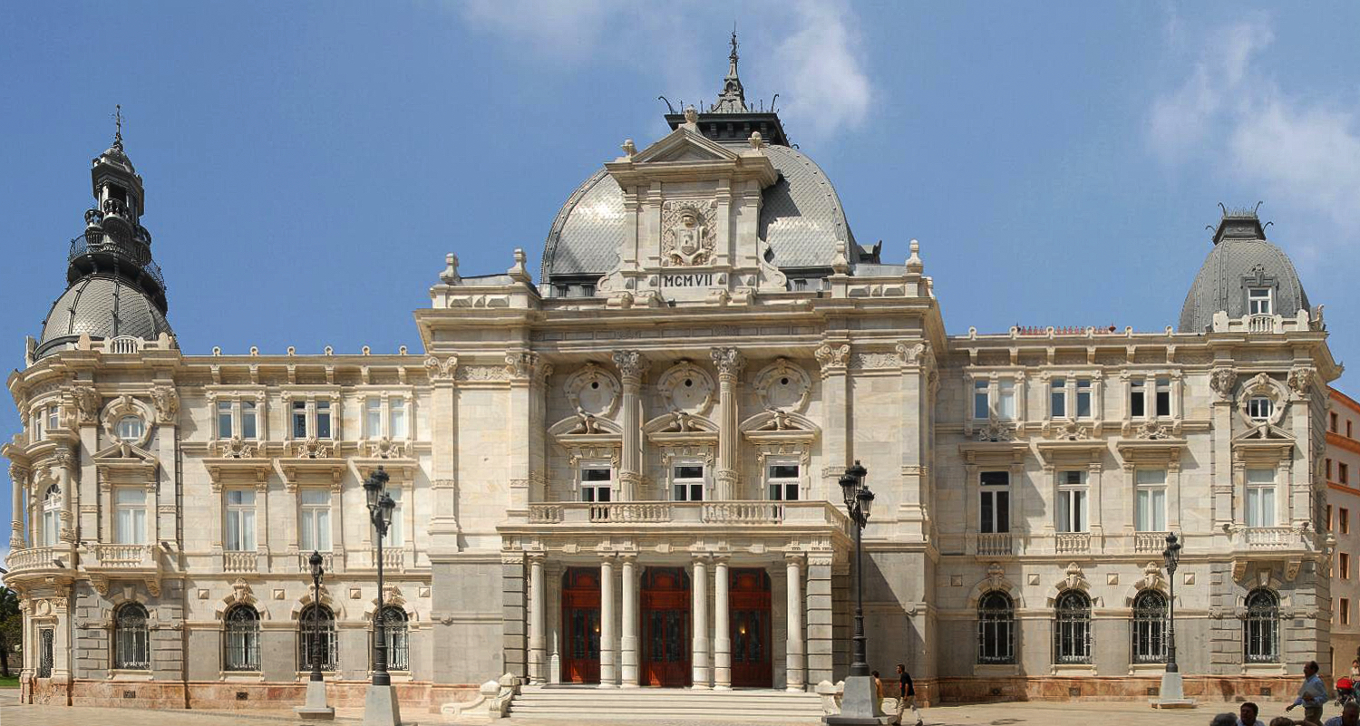Fachada de un edificio monumental de piedra con tres cúpulas y una escalinata central.
