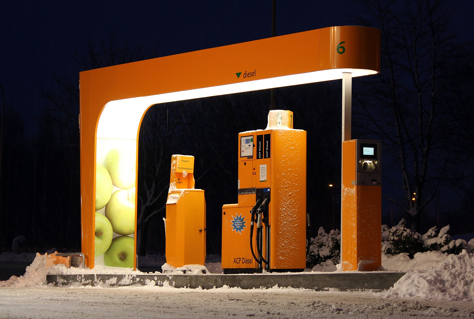 Un surtidor naranja lleva el rótulo «diesel»; la escena está cubierta de nieve.