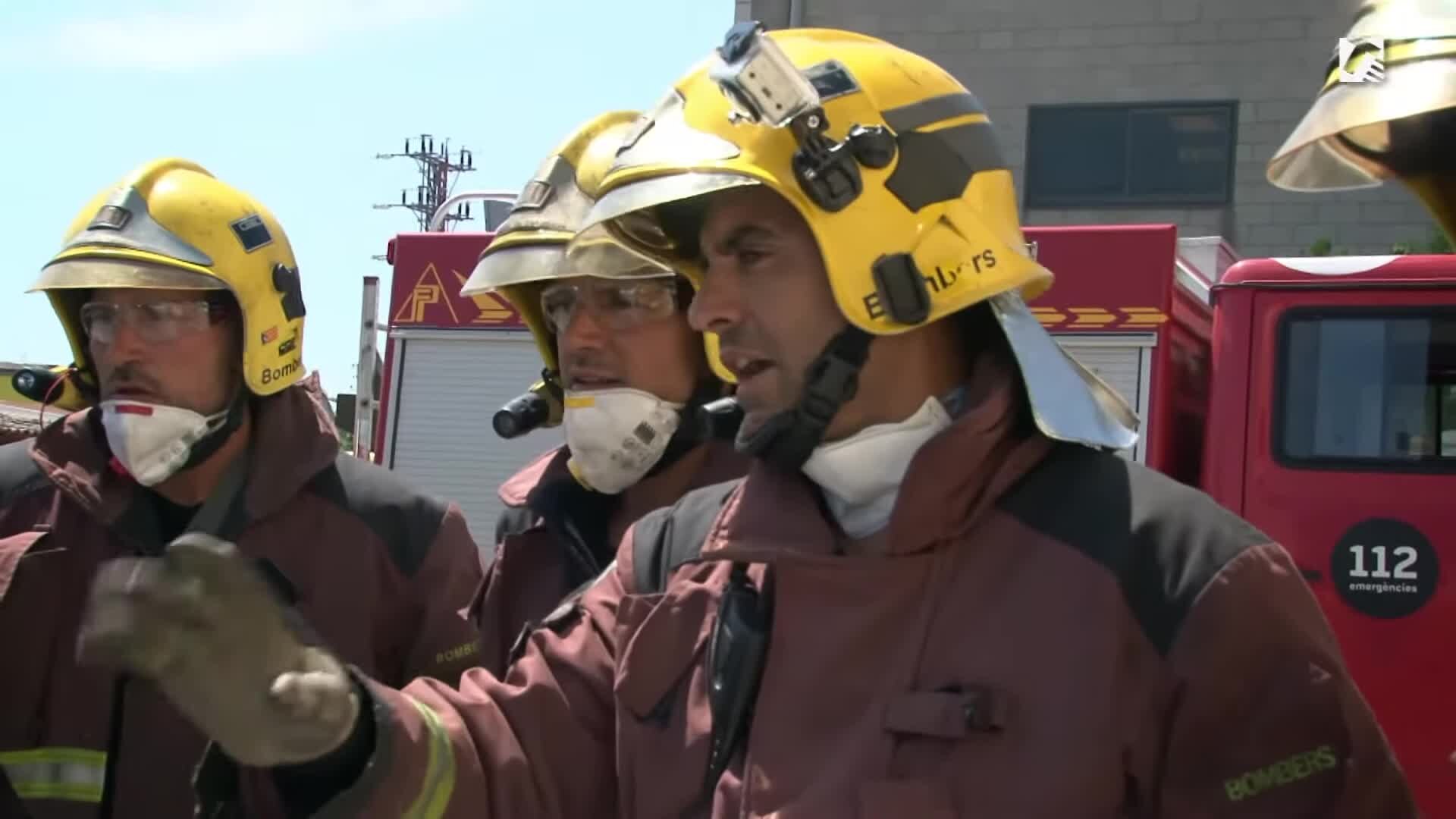 Varios bomberos con casco y equipo de protección junto a vehículos de emergencia.