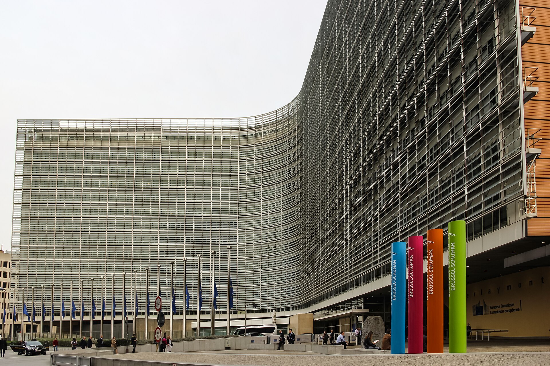 Fachada acristalada con banderas de la Unión Europea y rótulos de la Comisión Europea.