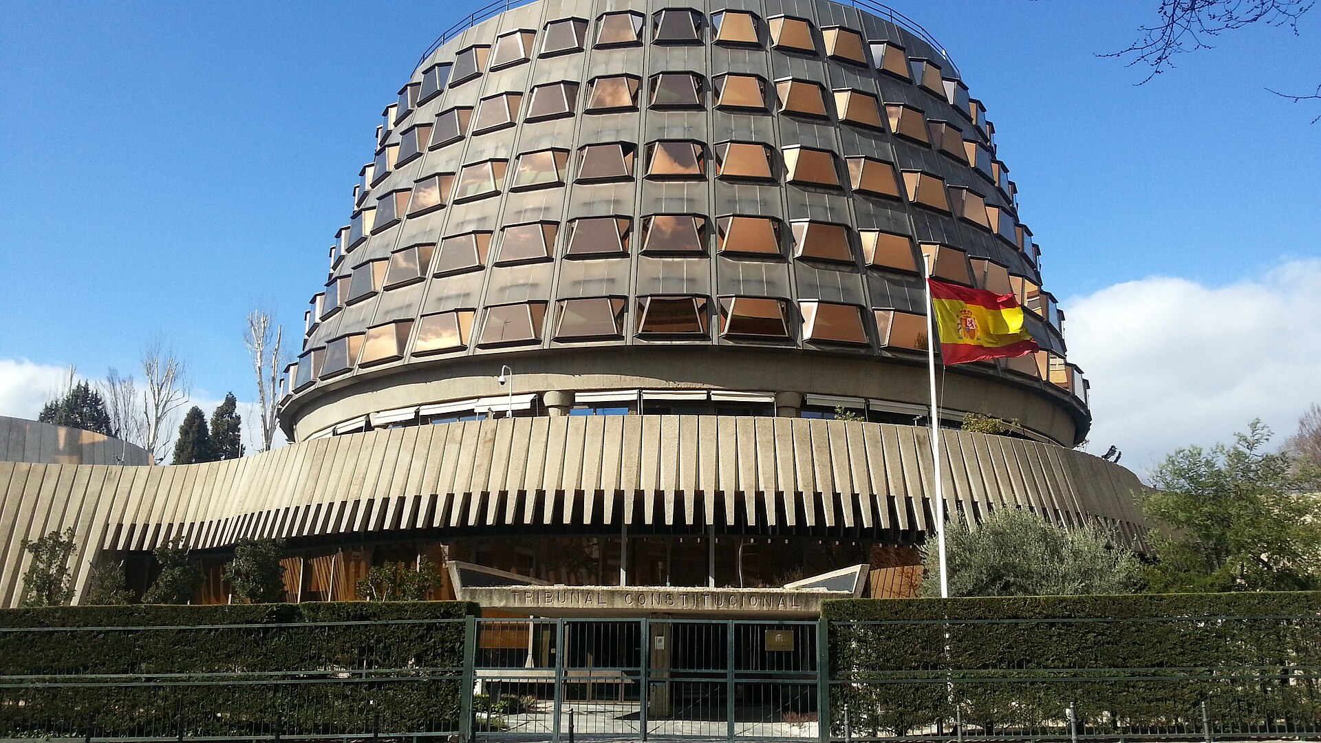 La fachada de un edificio muestra el rótulo «Tribunal Constitucional» y una bandera española.
