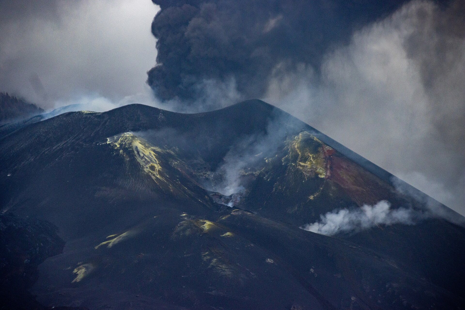 Vista cercana de un cono volcánico oscuro con varias emisiones de humo.