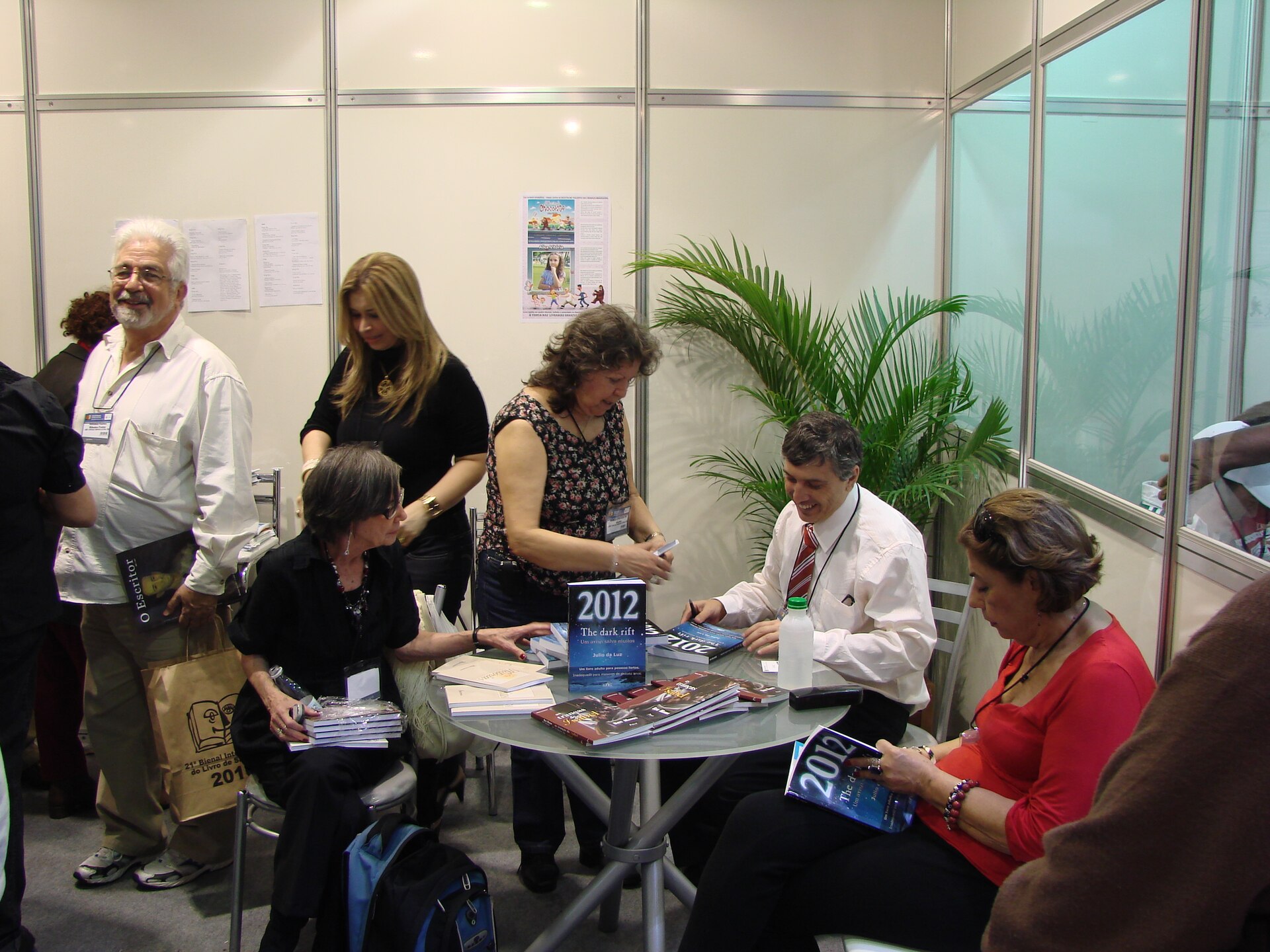 Personas conversan y consultan libros en un puesto editorial.