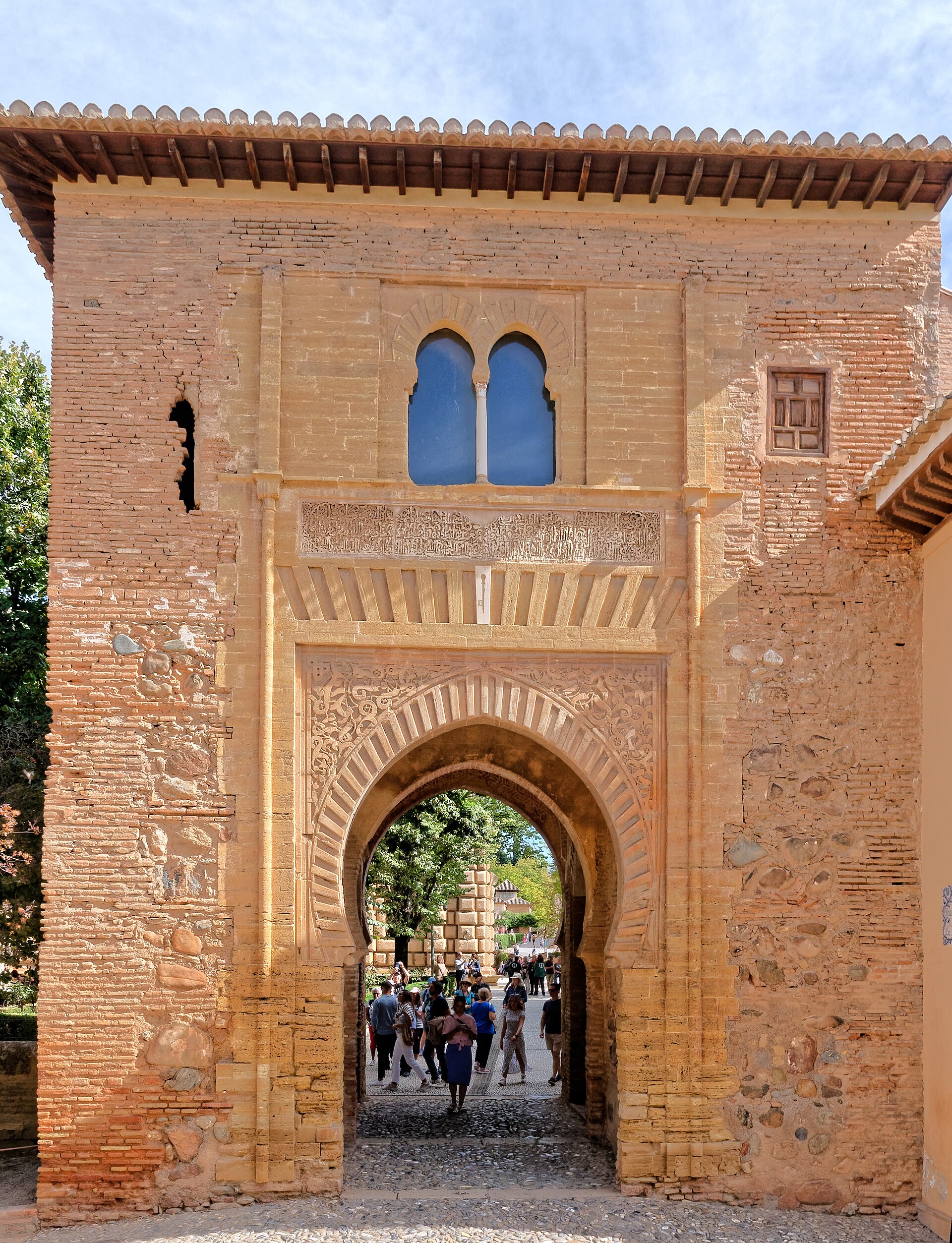 Arco monumental de un conjunto histórico, con visitantes atravesando la entrada.